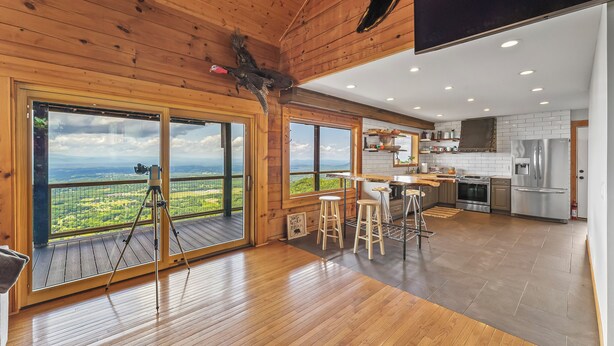 A spacious kitchen with wooden floors, large windows, and a view of the countryside.