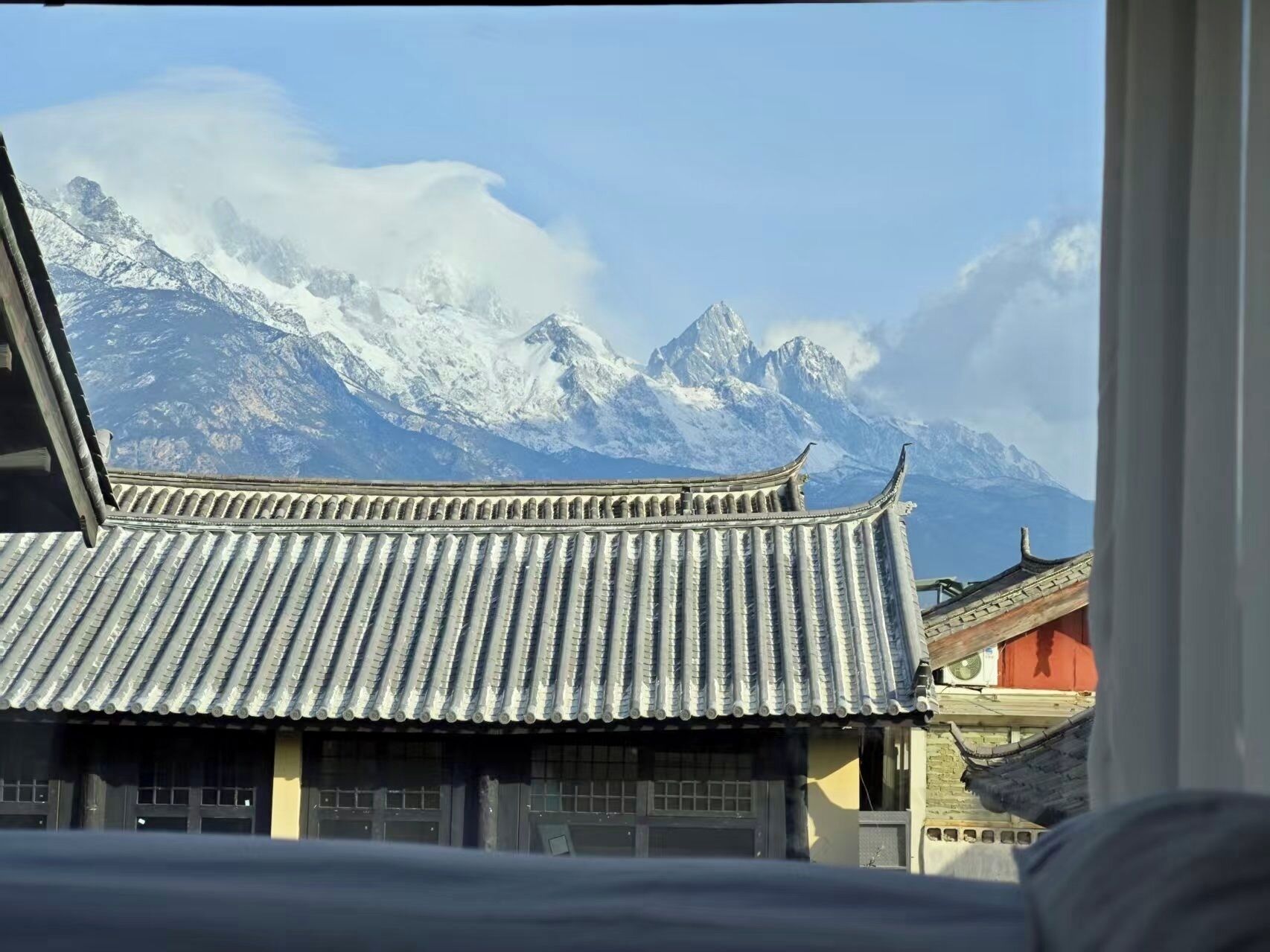 Un edificio tradicional con techo de tejas y vista a montañas nevadas.