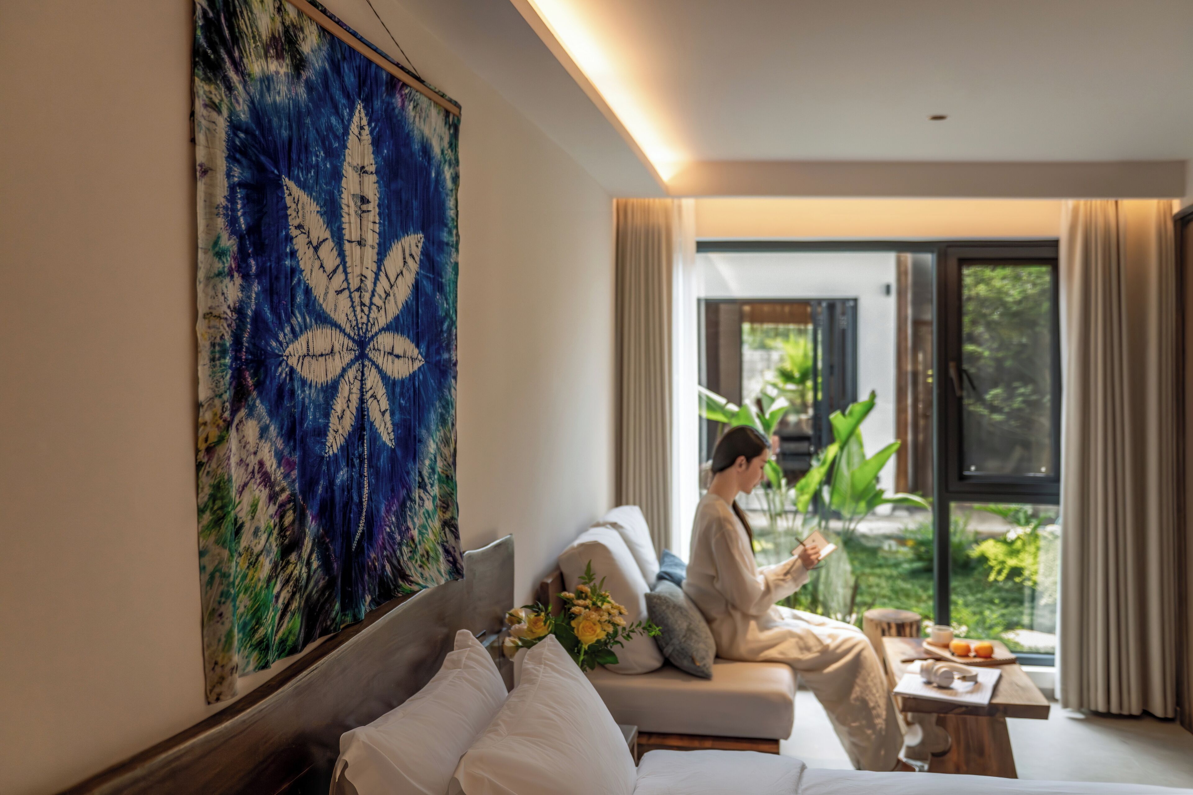 A modern living room with a large abstract painting, a sofa, and a person reading a book.