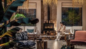 A cozy living room with a fireplace, comfortable seating, and a large window with a view of greenery.