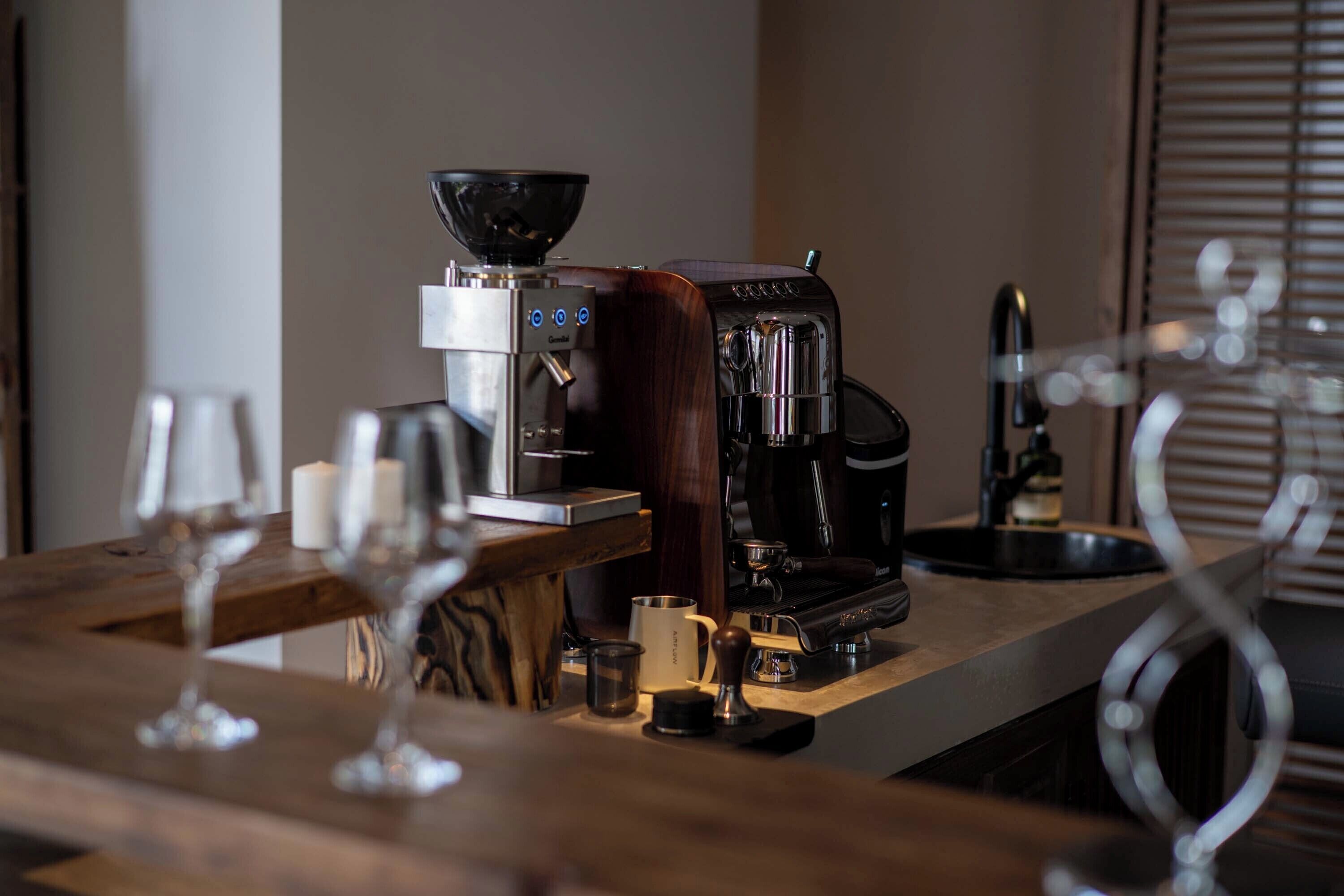 A coffee machine and a glass on a wooden counter.