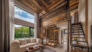 A modern living room with a wooden ceiling, a sofa, a coffee table, and a staircase.
