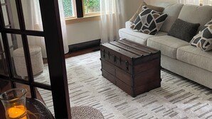 Un salon comprenant un canapé, une commode en bois, un pouf en osier, un porte-bougie en verre et un ventilateur de plafond.