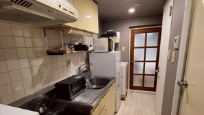 A compact kitchen with a stove, microwave, and sink. - GuestHouseAQUA203 (Hiroshima)