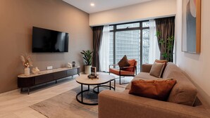 A modern living room with a sofa, coffee table, and TV. - Eaton Residences by Sutera@klcc (Kuala Lumpur)