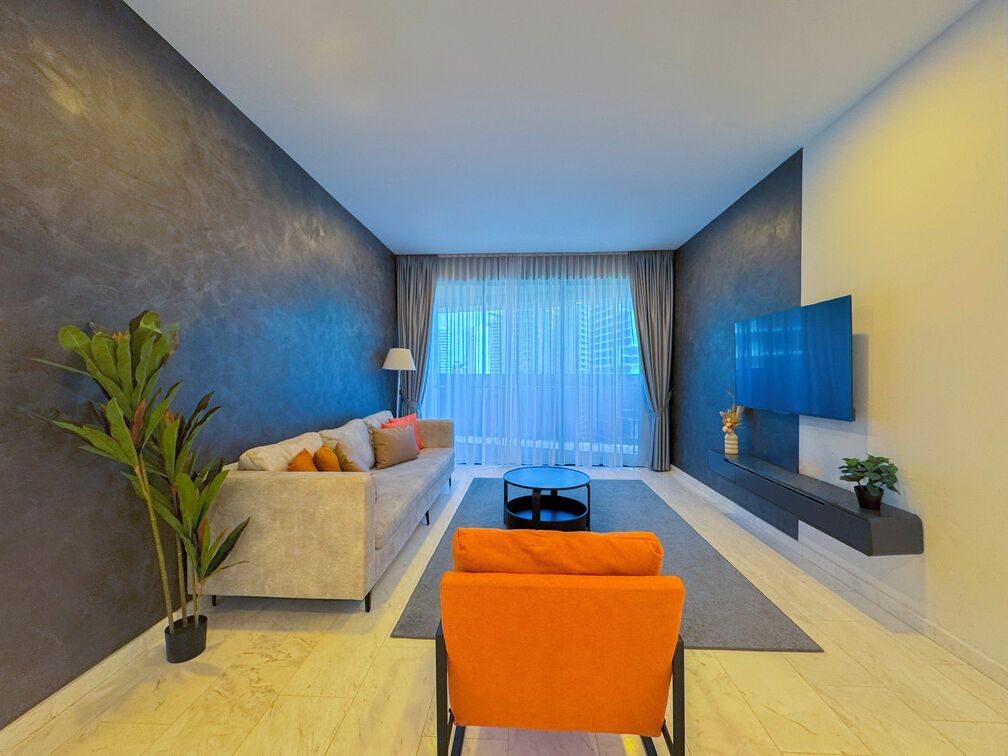 Ein modernes Wohnzimmer mit einer Couch, einem Couchtisch und einem an der Wand montierten Fernseher.