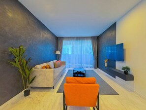 Un salon moderne avec un canapé, une table basse et un téléviseur fixé au mur.