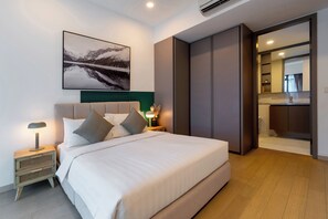 Une chambre moderne avec un grand lit, une table de chevet avec une lampe, un tableau accroché au mur et un placard à portes coulissantes.