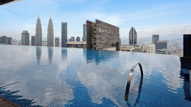 A rooftop infinity pool with a city skyline view, including the Petronas Towers. - Eaton Residences by Sutera@klcc (Kuala Lumpur)