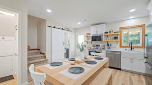Una cocina moderna con armarios blancos, una mesa de comedor de madera y un horno empotrado.