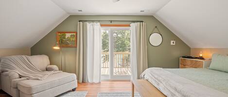 Une chambre confortable avec un lit, une chaise, un ventilateur de plafond et un balcon agrémenté de rideaux.