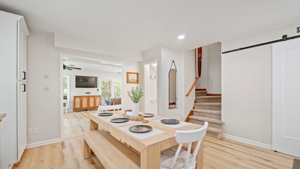 Una cocina moderna con piso de madera, una mesa de comedor preparada para cuatro personas y una escalera que sube a otro nivel.