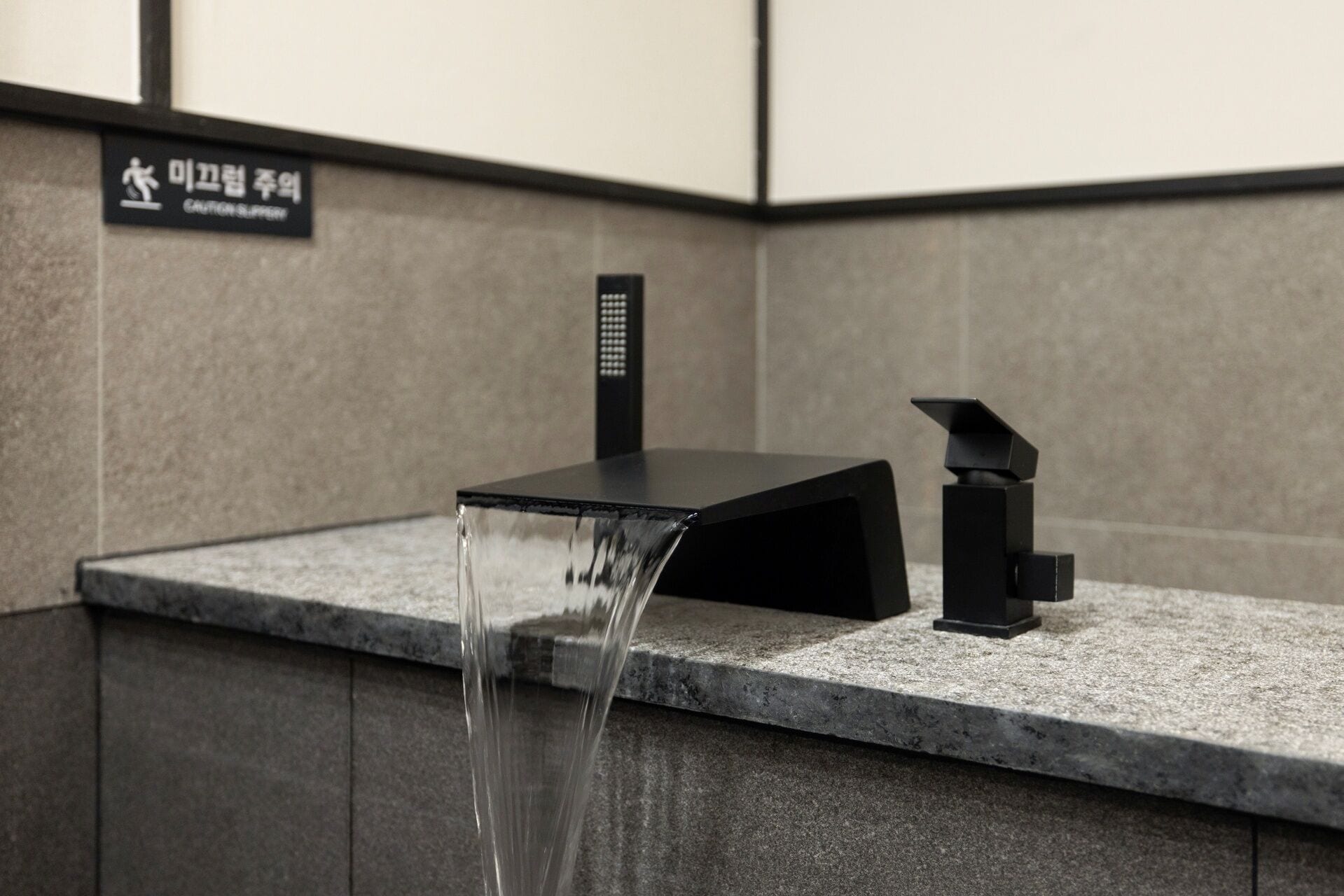A modern bathroom with a black faucet and a water spout.