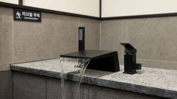 A modern bathroom with a black faucet and a water spout.