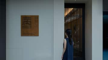 A woman standing in front of a building with a wooden plaque on the wall.