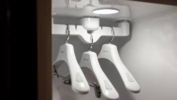 A white wall with three white towel racks labeled "LG Styler" and a ceiling light fixture.