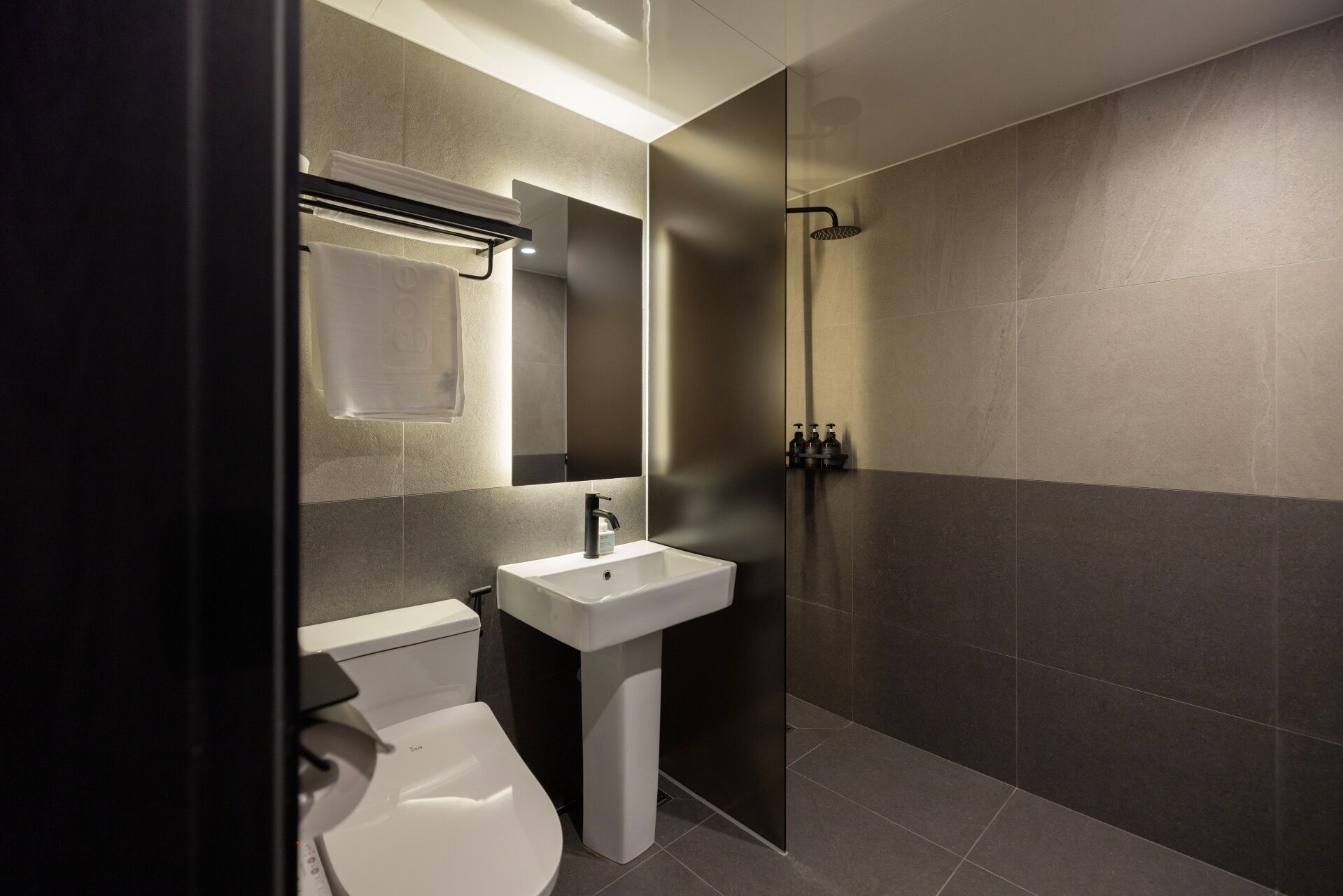 A modern bathroom with a toilet, sink, and shower.