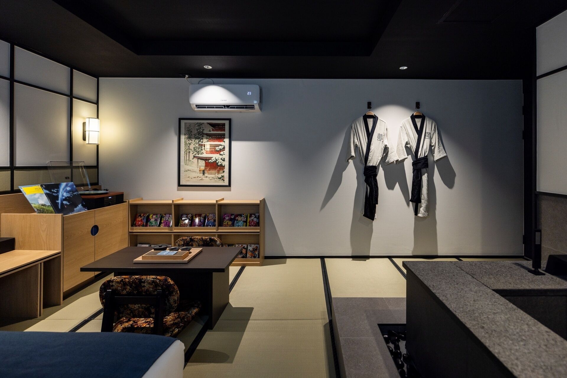 A modern room with a sofa, a table with a tray, a bookshelf, and a wall-mounted air conditioner.