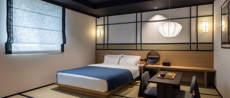 Una habitación de hotel moderna con cama, mesita de noche, silla y escritorio con lámpara.