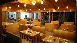Un restaurant situé à l’intérieur, avec un plafond et des murs en bois, des tables recouvertes de nappes blanches et des chaises.