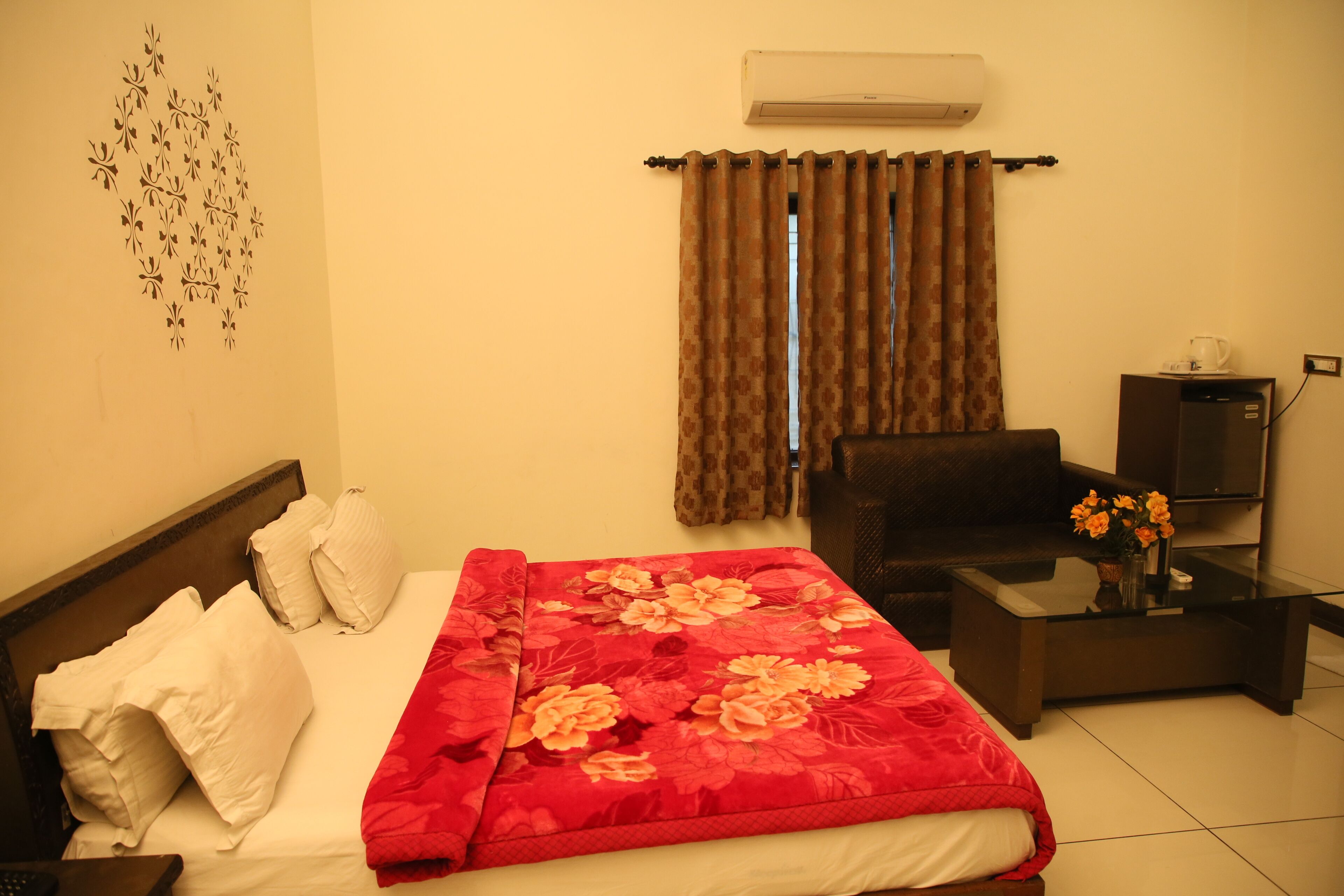 A hotel room with a bed, a sofa, a coffee table, and an air conditioner.