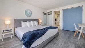 A hotel room with a bed, bedside tables, a desk, and a chair. - Spacious Beach Condo Double Suite for Couples Getaway (Myrtle Beach)