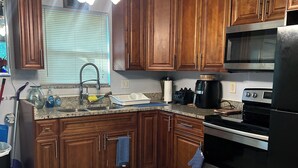 Una cocina con armarios de madera, un refrigerador de acero inoxidable, un microondas y una estufa.