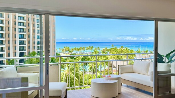 A balcony with a view of the ocean, a white sofa, a small round table, and a chair. - Wake Up to Waves Oceanview Retreat (Car Available) (Honolulu)