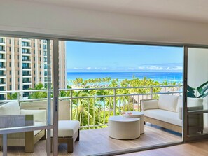 A balcony with a view of the ocean, a white sofa, a small round table, and a chair. - Wake Up to Waves Oceanview Retreat (Car Available) (Honolulu)