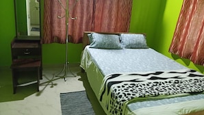 A bedroom with a bed, a nightstand, a mirror, and a floor lamp. - Riverside Homestay by nature  (Mankulam)