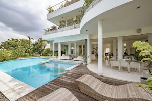 Uma casa moderna com piscina, área de estar externa e varanda com plantas.