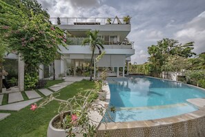 A modern two-story building with a swimming pool, surrounded by well-maintained greenery and a clear sky. - Holistic Horizon Bali (Kerobokan)
