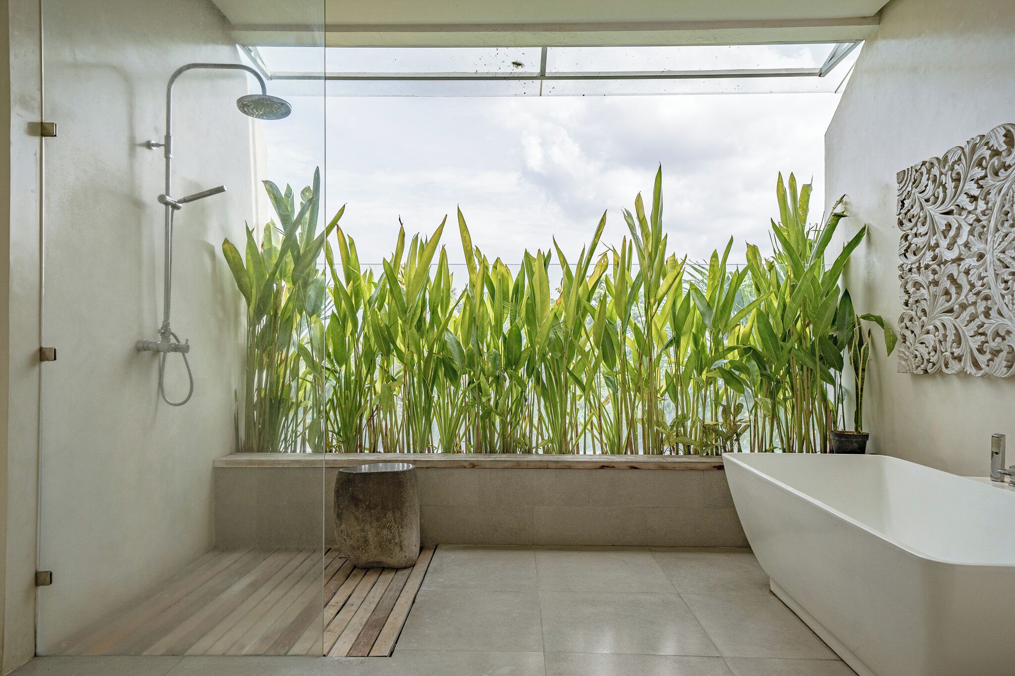 Une salle de bain moderne dotée d’un puits de lumière, d’une baignoire sur pieds et d’un espace douche.