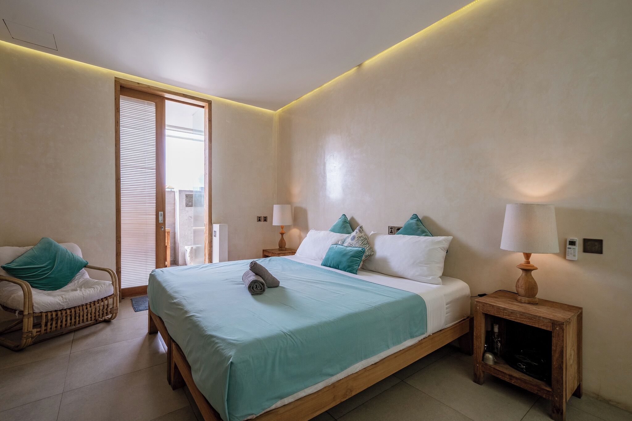A bedroom with a bed, bedside tables, a chair, and a window.