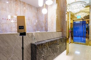 A hotel reception area with a marble wall, a digital information kiosk, and a chandelier. - Signature Denbasta Hotel (Busan)
