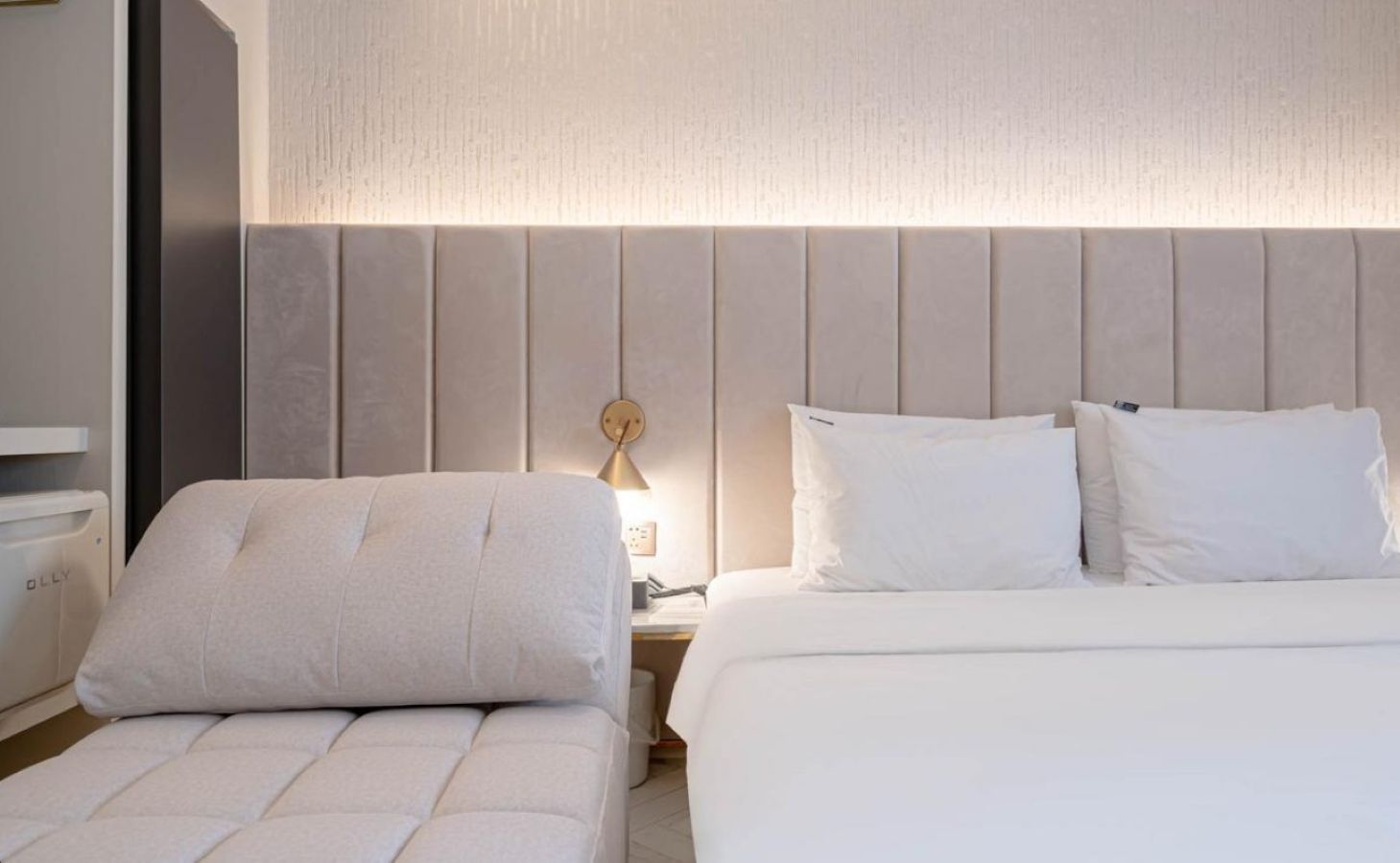 A hotel room with a bed, a bedside table, a lamp, and a chair.