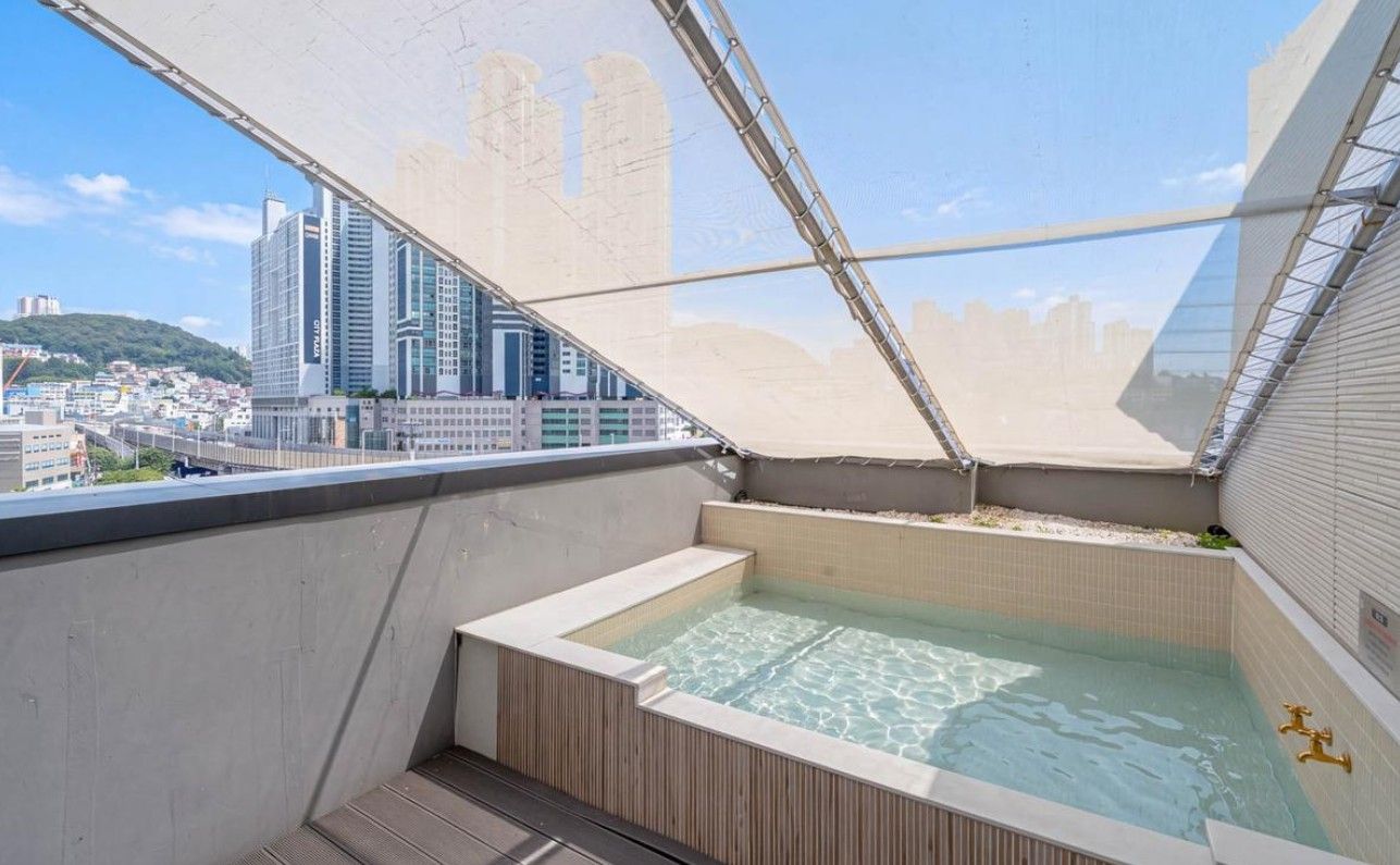 A rooftop hot tub with a cityscape view, surrounded by a metal canopy.