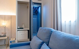 Egy szoba, melyben egy kék kanapé, egy kis asztal lámpával és egy minibar található.