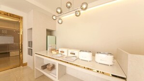 A modern kitchen with a white countertop, three BLIV toasters, and a unique spherical light fixture. - Signature Denbasta Hotel (Busan)