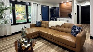 A modern living room with a leather sectional sofa, a coffee table, and a ceiling fan. - Marvelous 3-bedroom house with AC in Charlotte (Charlotte)
