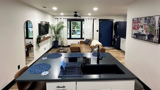 A modern kitchen with a central island, white cabinets, and a dining area with a brown leather couch. - Marvelous 3-bedroom house with AC in Charlotte (Charlotte)