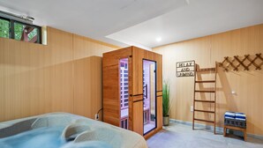 A spa room with a hot tub, wooden walls, a ladder, and a sign that reads "RELAX AND UNWIND".