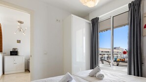 Ein Hotelzimmer mit einem großen Bett, einem Kleiderschrank, einer Küchenzeile und einem Balkon mit Blick auf die Stadt.