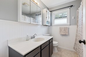 Un bagno con doppio lavandino, servizi igienici, una finestra e una tenda per la doccia.