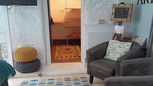 Una sala de estar acogedora con un sofá gris, un tapete estampado y un pequeño reposapiés.
