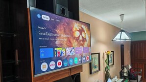 Ein an der Wand befestigter Fernseher zeigt eine Streaming-Dienstanwendung mit verschiedenen App-Symbolen und einem Filmtitel.