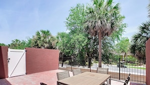 An outdoor patio with a table and chairs, surrounded by a brick wall and a metal fence. - 4 Bed Villa-Sleeps 8-Pool-Gym-15 min to Disney (Kissimmee)
