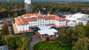A large, multi-story building with a central courtyard, surrounded by trees and a parking lot.