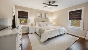 A bedroom with a bed, bedside tables, a ceiling fan, and a TV.