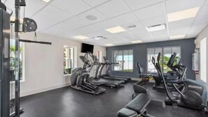 Un gimnasio con cintas de correr, máquinas elípticas y equipo de levantamiento de pesas.